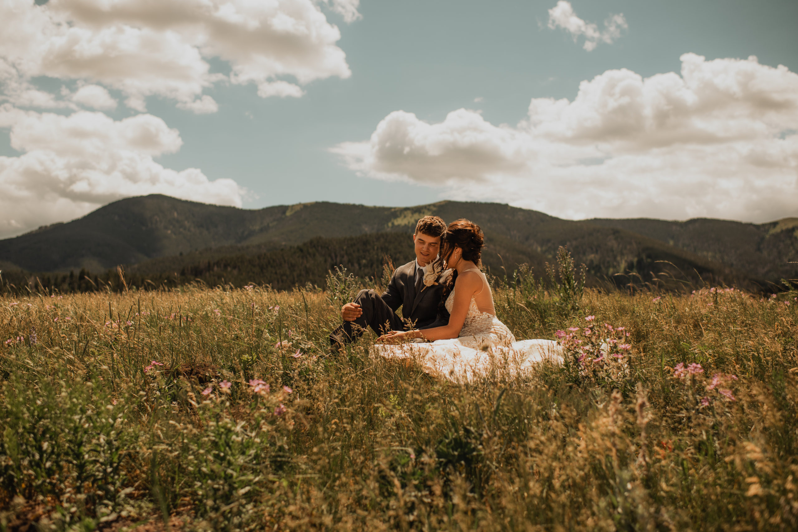 A newly married couple embracing in a field of flowers in the Highwood Mountains of Montana.