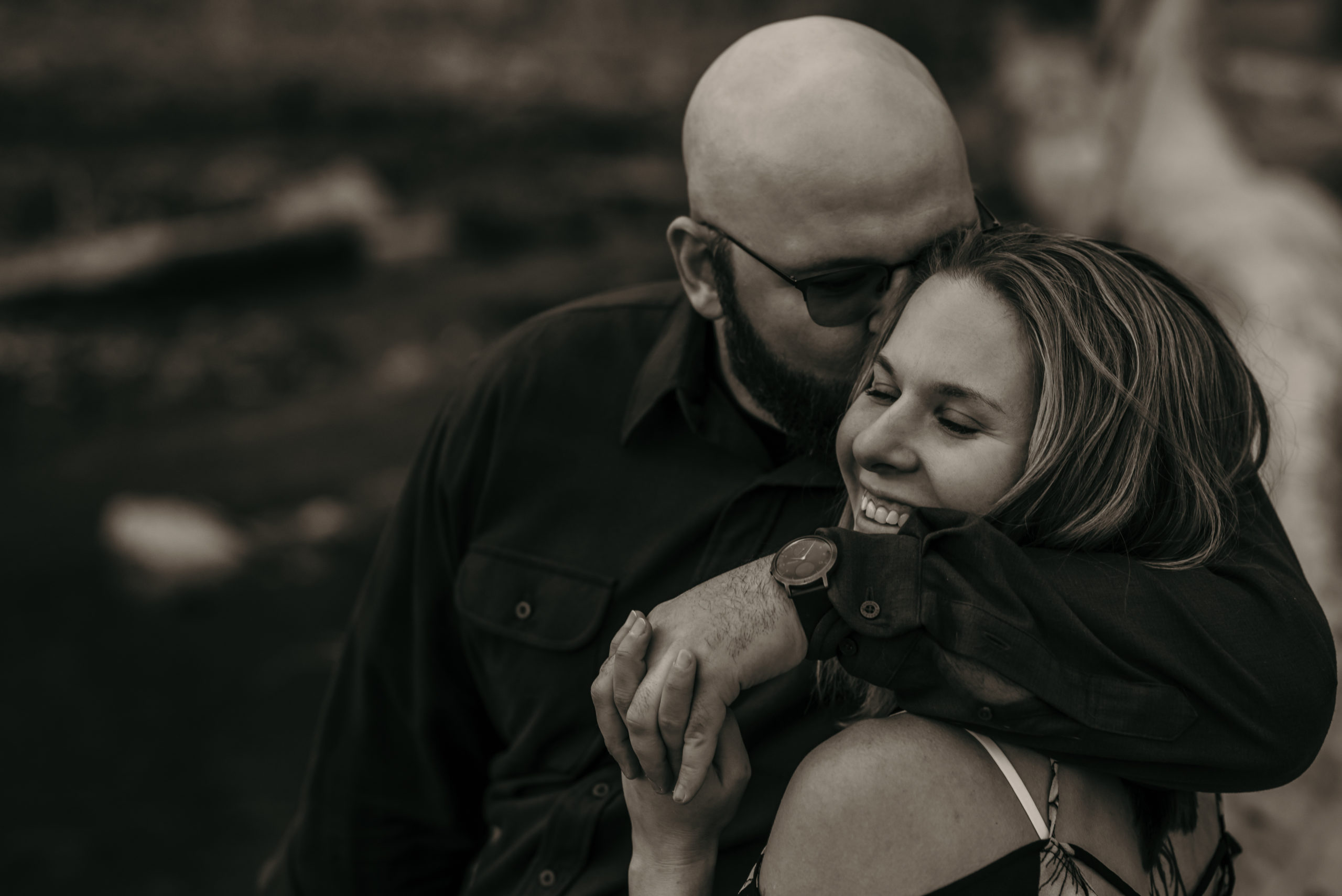 An engaged couple embracing near a creek in Montana.