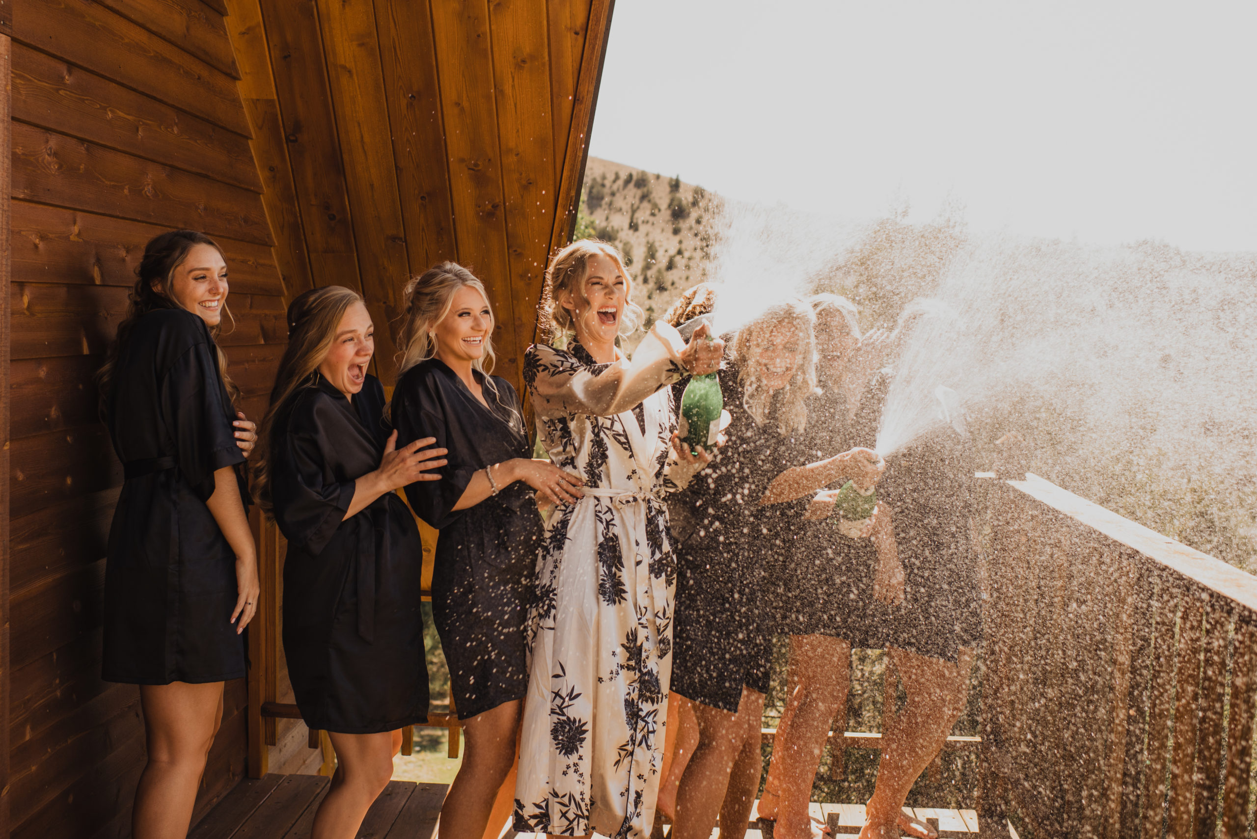 A bride celebrating by popping champagne with her bridesmaids in Southwest Montana.