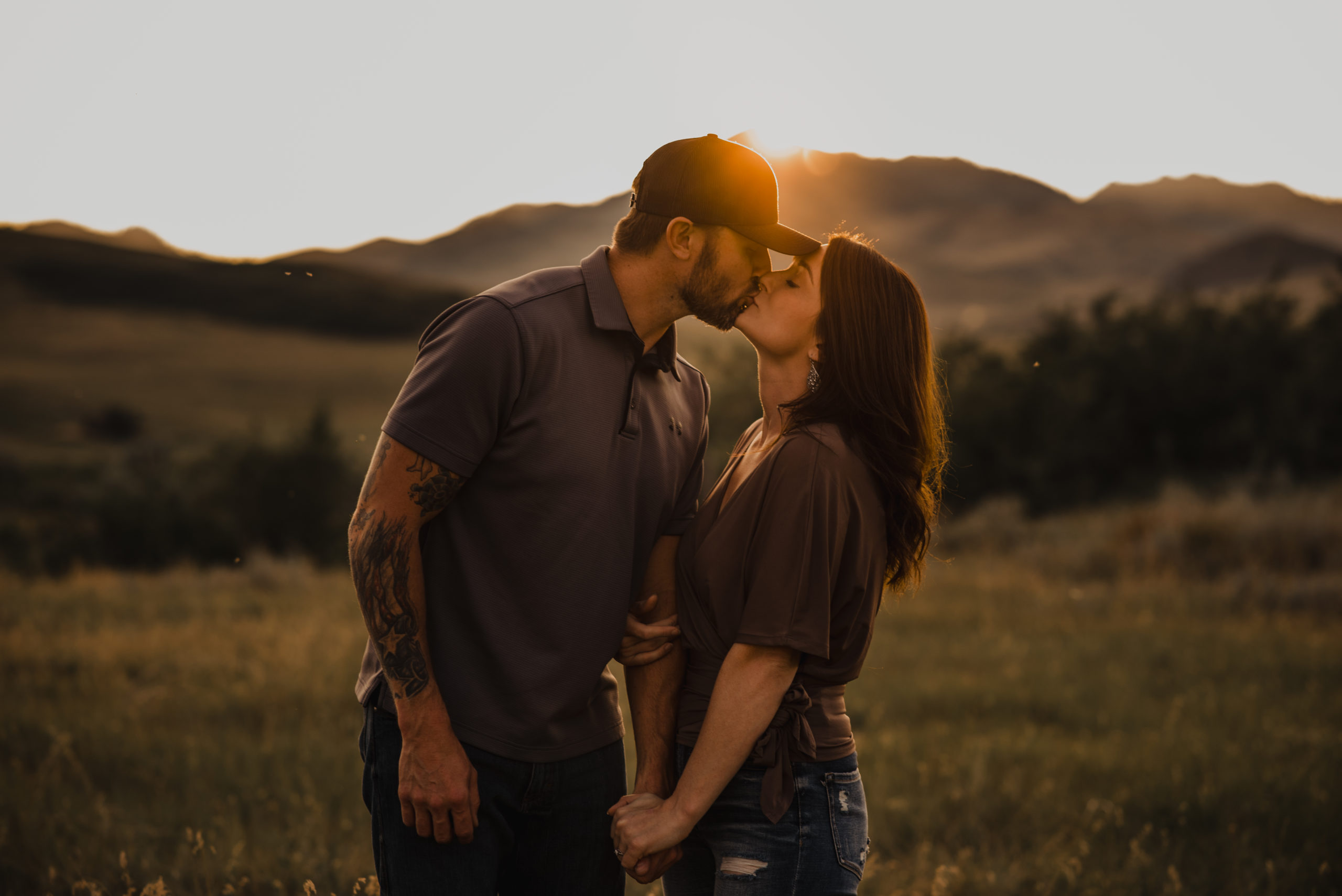 An engaged couple kissing with a backdrop of Mountains in Havre, Montana.
